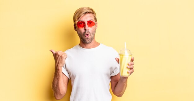 Uomo adulto biondo che sembra stupito nell'incredulità con un milkshake