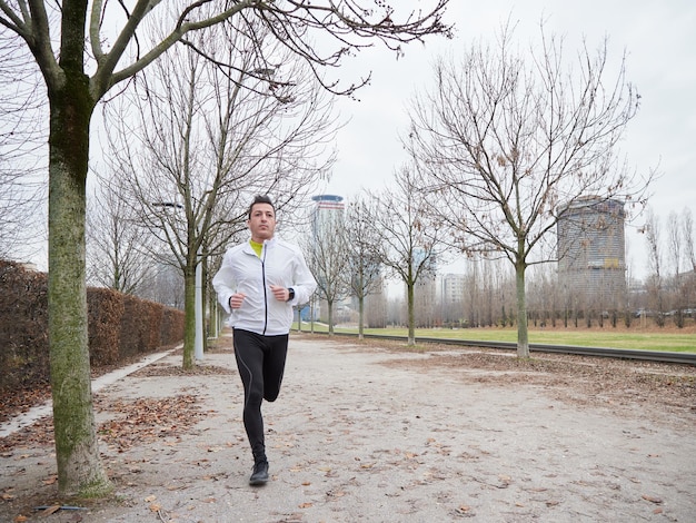 Uomo adulto che corre nel parco in inverno con lo sfondo della città