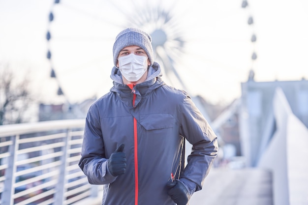 uomo adulto che fa jogging in città con le maschere durante la pandemia di blocco