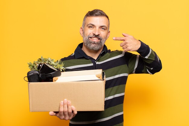 Uomo adulto che sorride fiduciosamente indicando il proprio ampio sorriso, positivo