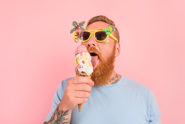 Uomo affamato con barba e tatuaggi mangia un grande gelato