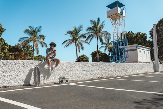 Uomo africano che ascolta musica con stereo vintage boombox all'aperto mentre si utilizza il telefono cellulare - Focus sul viso