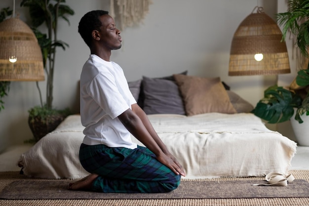 Uomo africano che pratica yoga e meditazione a casa