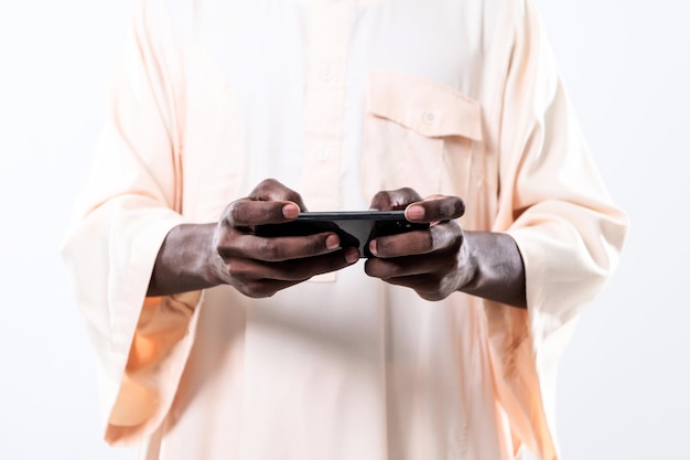 uomo africano che usa lo smartphone e indossa abiti traditioinal sudan isolati su sfondo bianco