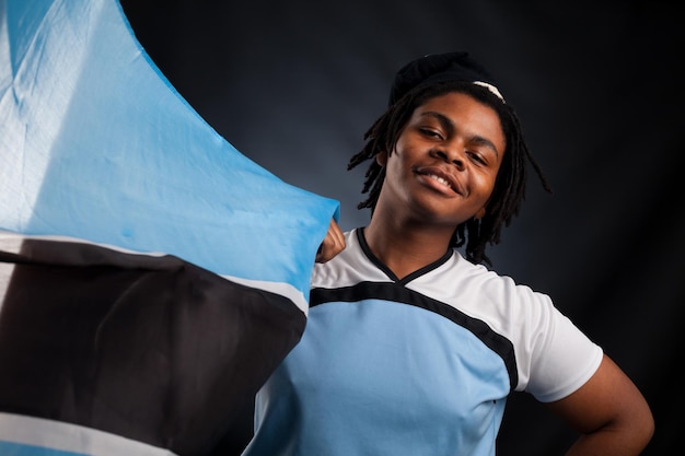 Uomo africano del Botswana con una bandiera sorridente in uno studio fotografico su uno sfondo scuro