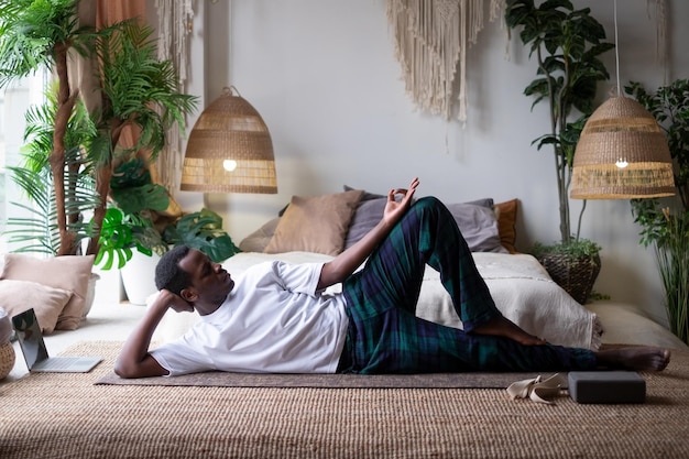 Uomo africano di yoga che fa posa di anantasana che si allena a casa