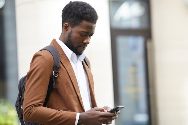 Uomo africano moderno che usando Smartphone all'aperto