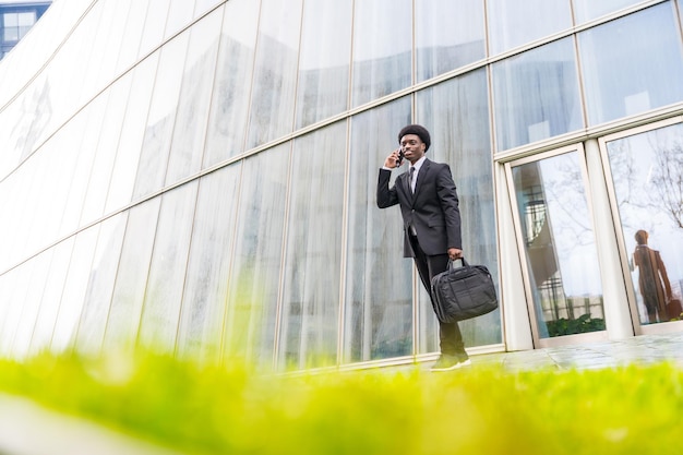 Uomo africano occupato che esce dall'ufficio parlando al cellulare