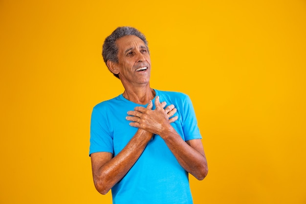 Uomo afro anziano con la mano sul petto con gratitudine