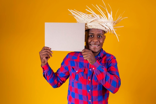 Uomo afro brasiliano che indossa abiti tipici per la Festa Junina con cartello con spazio per il testo