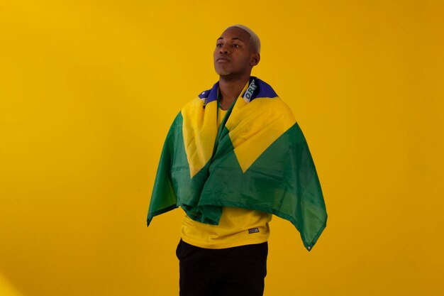 Uomo afro brasiliano sostenitore della squadra di calcio brasiliana nella coppa del 2022 con la bandiera del Brasile e con le espressioni facciali