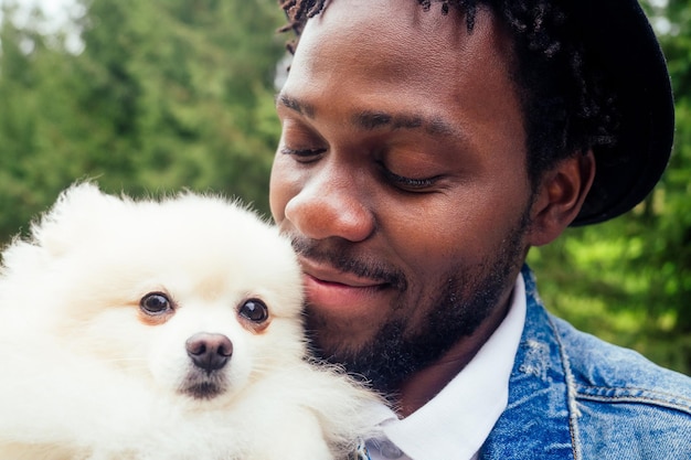 Uomo afro che abbraccia il suo spitz soffice nel parco