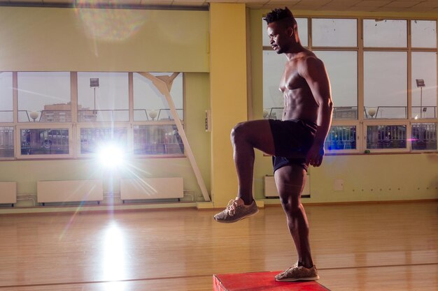 Uomo afro che fa esercizio con una scatola adatta in palestra.