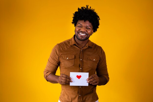 Uomo afro che tiene una lettera d'amore su sfondo giallo con spazio libero per il testo lettera di san valentino