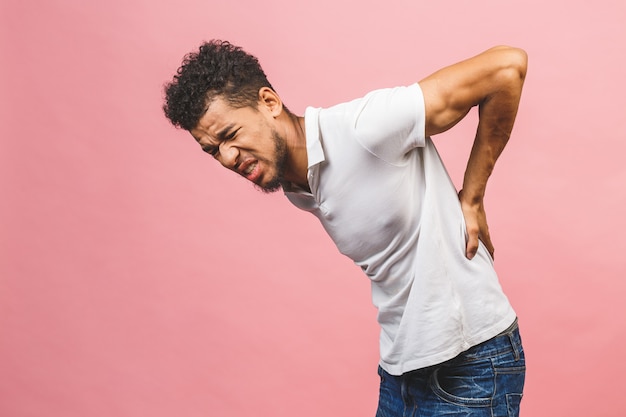 Uomo afro con in piedi su sfondo rosa isolato Sofferenza di mal di schiena, toccando la schiena con la mano, dolore muscolare.