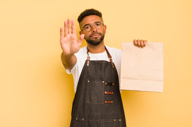 Uomo afro cool che sembra serio mostrando il palmo aperto facendo gesto di arresto fattorino e concetto di fast food