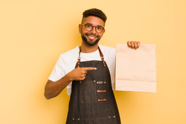 Uomo afro cool che sorride allegramente sentendosi felice e indicando il fattorino laterale e il concetto di fast food