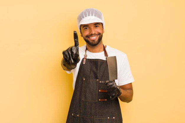 Uomo afro cool che sorride con orgoglio e sicurezza facendo il concetto di macellaio numero uno