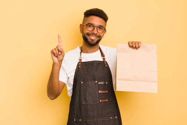 Uomo afro cool sorridente e dall'aspetto amichevole che mostra il fattorino numero uno e il concetto di fast food