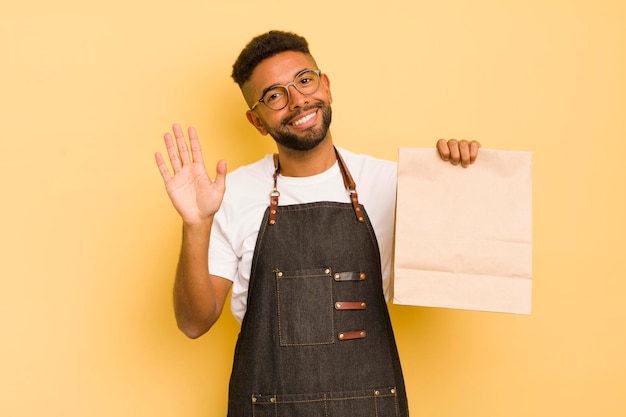 Uomo afro cool sorridente felicemente agitando la mano dandoti il benvenuto e salutandoti fattorino e concetto di fast food