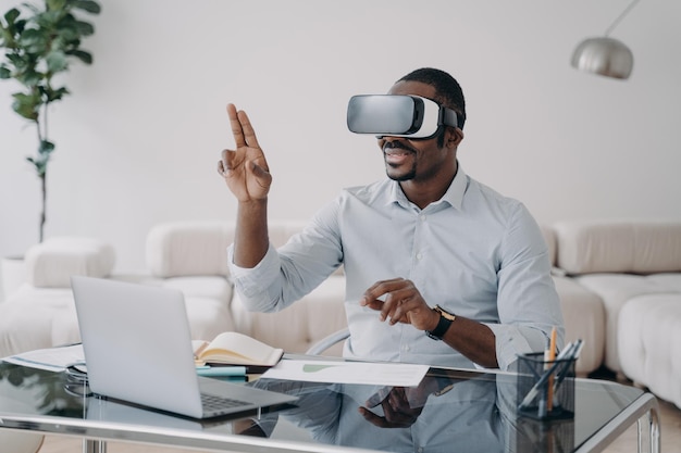 Uomo afro eccitato con occhiali vr sul posto di lavoro a casa L'uomo d'affari ha una riunione virtuale