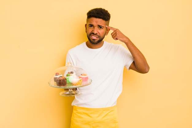 Uomo afro nero che si sente confuso e perplesso mostrando che sei un pazzo concetto di torte fatte in casa