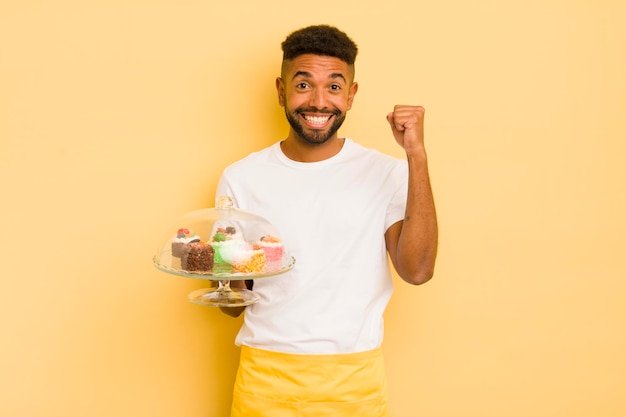 Uomo afro nero che si sente scioccato ridendo e celebrando il concetto di torte fatte in casa di successo