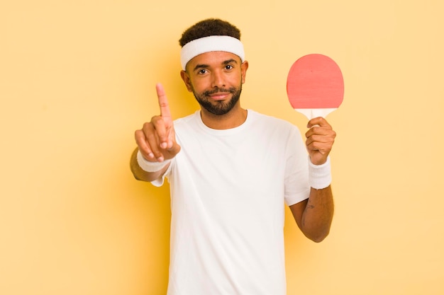 Uomo afro nero che sorride con orgoglio e sicurezza facendo il concetto di pingpong numero uno