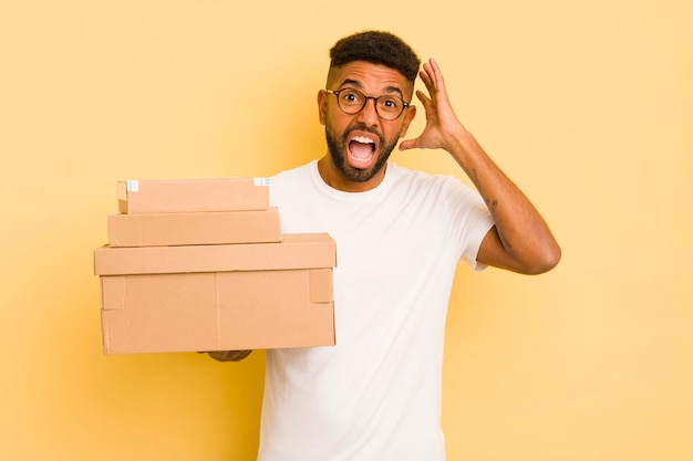 Uomo afro nero che urla con le mani in alto nel concetto di scatole di spedizione aerea