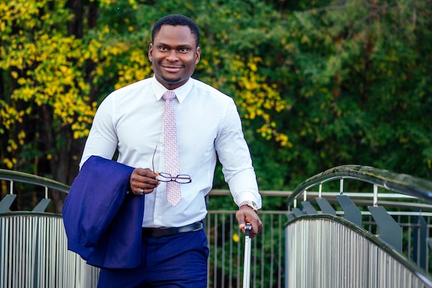 Uomo afroamericano ben vestito e di successo uomo d'affari africano treno a piedi alla stazione degli autobus della stazione ferroviaria. un viaggio a un incontro di lavoro nella capitale ai partner commerciali