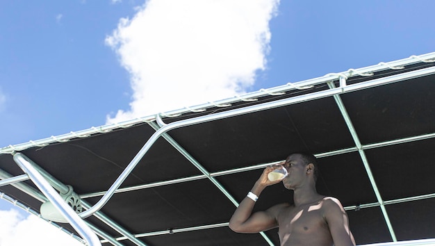 Uomo afroamericano che beve nel gazebo della spiaggia