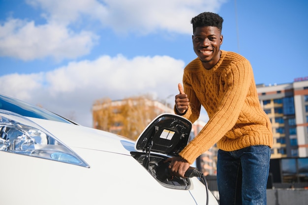 Uomo afroamericano che carica la sua auto elettrica.