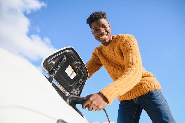 Uomo afroamericano che carica la sua auto elettrica.