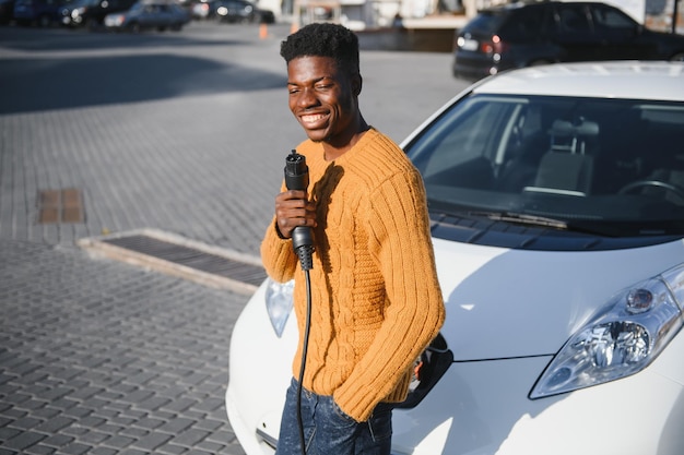 Uomo afroamericano che carica la sua auto elettrica.