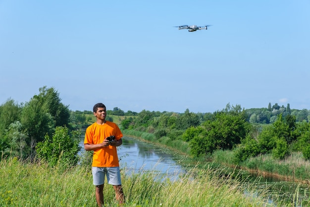 Uomo afroamericano che fa funzionare un drone con il controller in mano sul prato