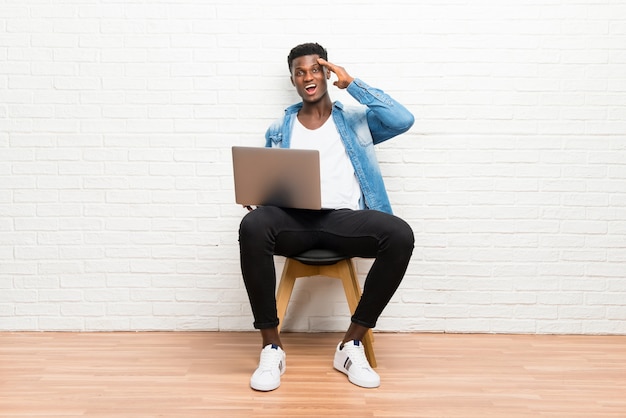 Uomo afroamericano che lavora con il suo laptop che intende realizzare la soluzione