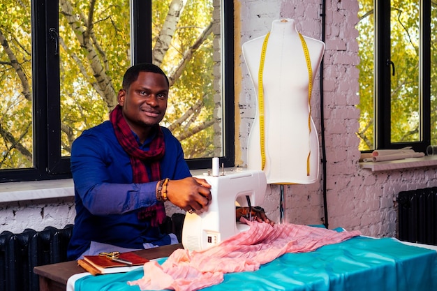 Uomo afroamericano che lavora in una sarta stilista di moda sartoria che lavora nel suo atelier