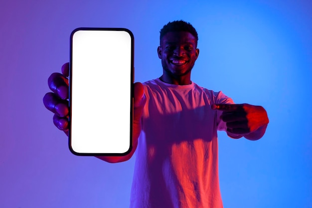 Uomo afroamericano che mostra uno schermo vuoto dello smartphone in illuminazione al neon