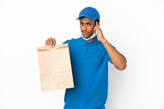 Uomo afroamericano che prende un sacchetto di cibo da asporto isolato su sfondo bianco pensando a un'idea