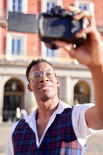 Uomo afroamericano che si fa un selfie con la sua fotocamera digitale Giovane blogger che si fa un selfie dal vivo