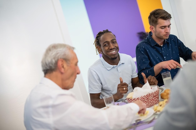 uomo afroamericano che si gode la cena iftar insieme alla moderna famiglia musulmana multietnica durante una festa del ramadan a casa