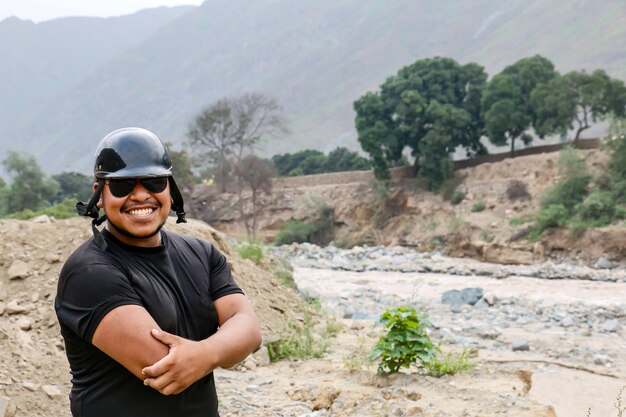 Uomo afroamericano con casco e gesti divertenti vicino a un fiume possente