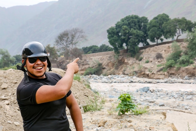 Uomo afroamericano con casco e gesti divertenti vicino a un fiume possente
