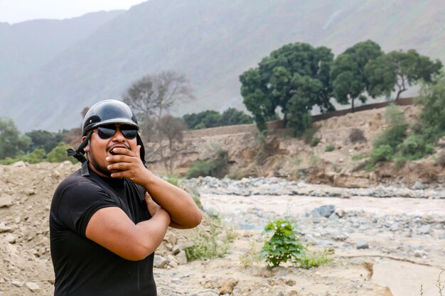 Uomo afroamericano con casco e gesti divertenti vicino a un fiume possente