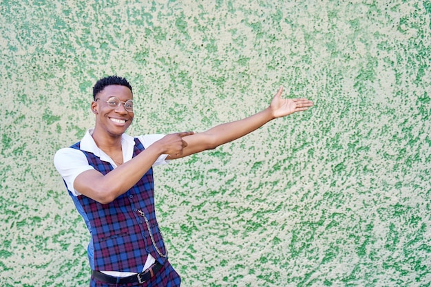 Uomo afroamericano con gli occhiali che puntano lontano con il dito isolato su sfondo verde