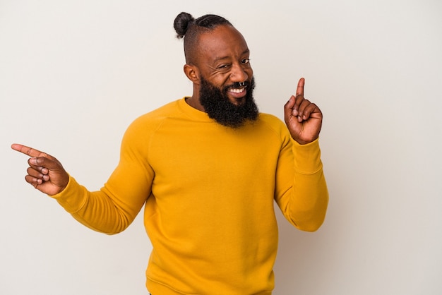 Uomo afroamericano con la barba isolata sulla parete rosa che punta a diversi spazi di copia, scegliendone uno, mostrando con il dito.