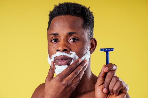 Uomo afroamericano con rasoio e schiuma da barba sul viso