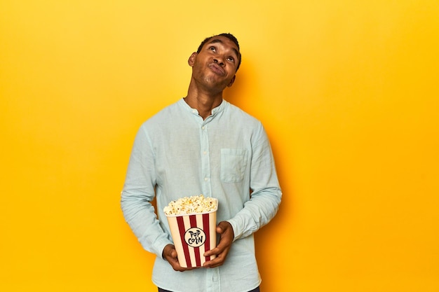 Uomo afroamericano con uno studio giallo di popcorn che sogna di raggiungere obiettivi e scopi
