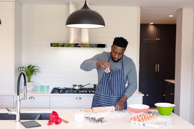 Uomo afroamericano concentrato che indossa il grembiule, cucinando in cucina