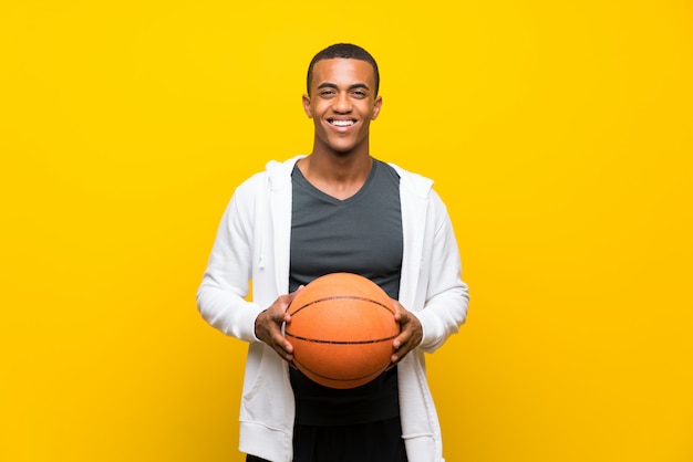 Uomo afroamericano del giocatore di pallacanestro sopra giallo isolato